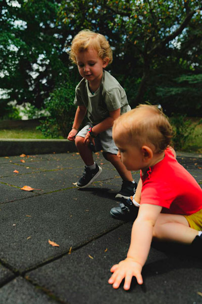 Dos niños corriendo y jugando en un parque verde, disfrutando de actividades deportivas al aire libre en un entorno natural y saludable.